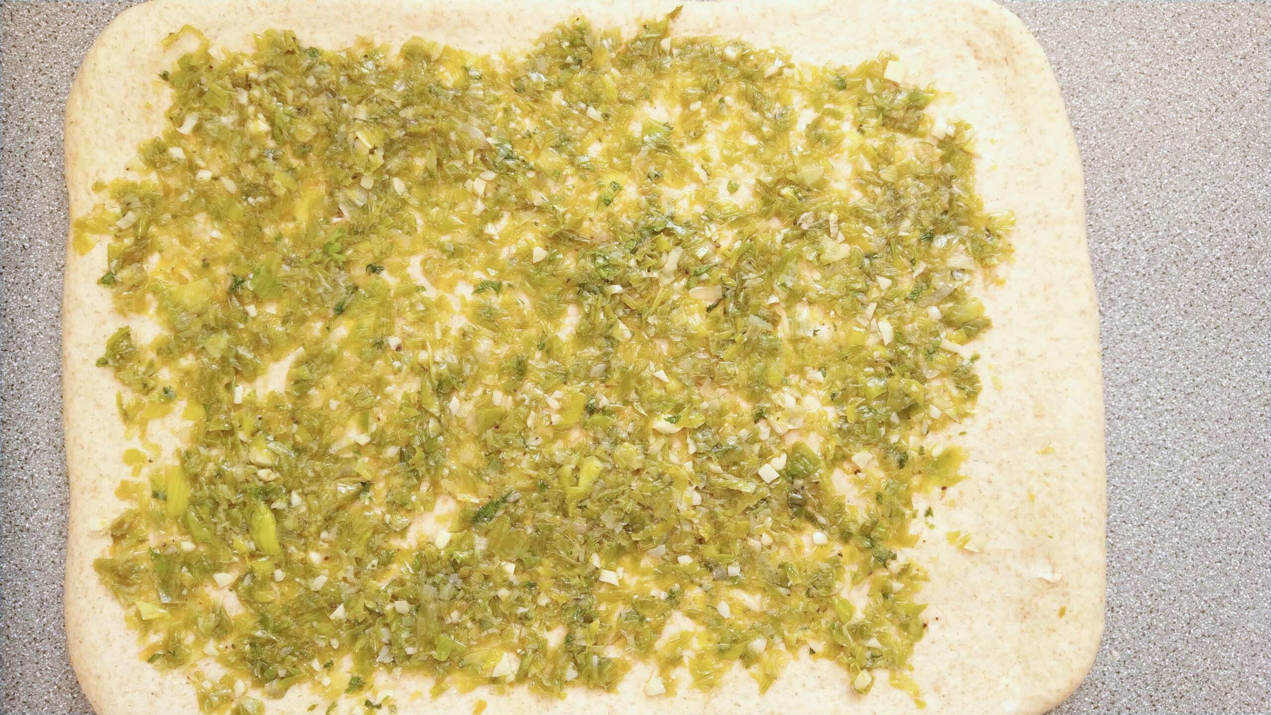Dough with sauteed leeks and garlic spread on it